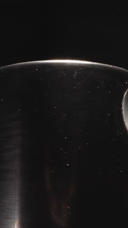 dirty black sprinkler cap from bottle with moisturizing spray on dark background. detailed cosmetic product for body care at bright light macro