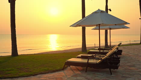 empty sun loungers face a colorful ocean sunset