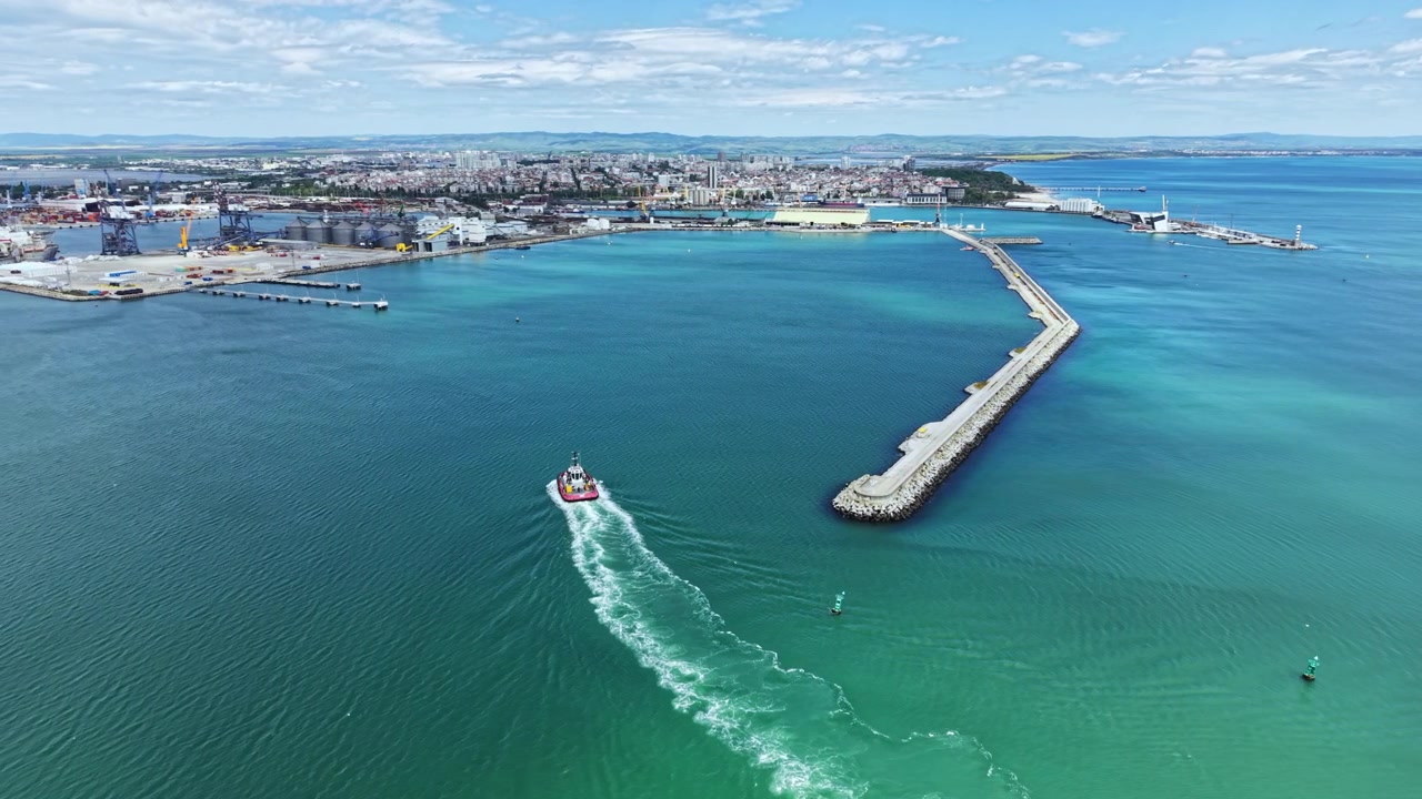 Vista di un porto con barche vicino a una città di giorno, che mostra la costa e corsi d'acqua in lontananza.
