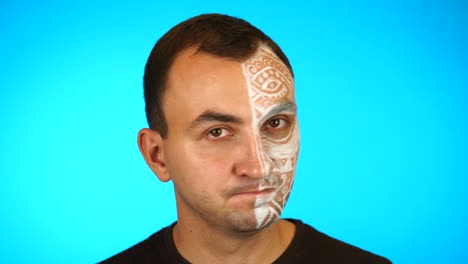 man with painted face is saying no by shaking head against blue background