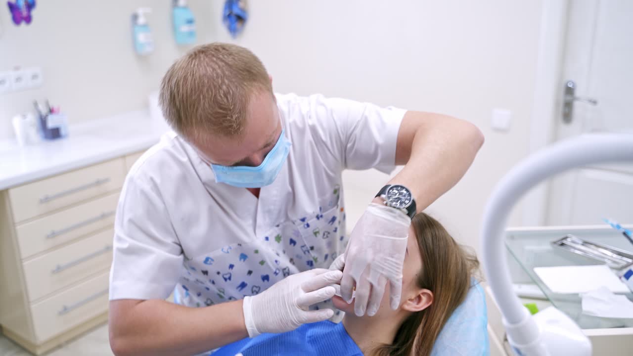 Young female patient in dentist office. Dentist examines the patient teeth at dental chair
