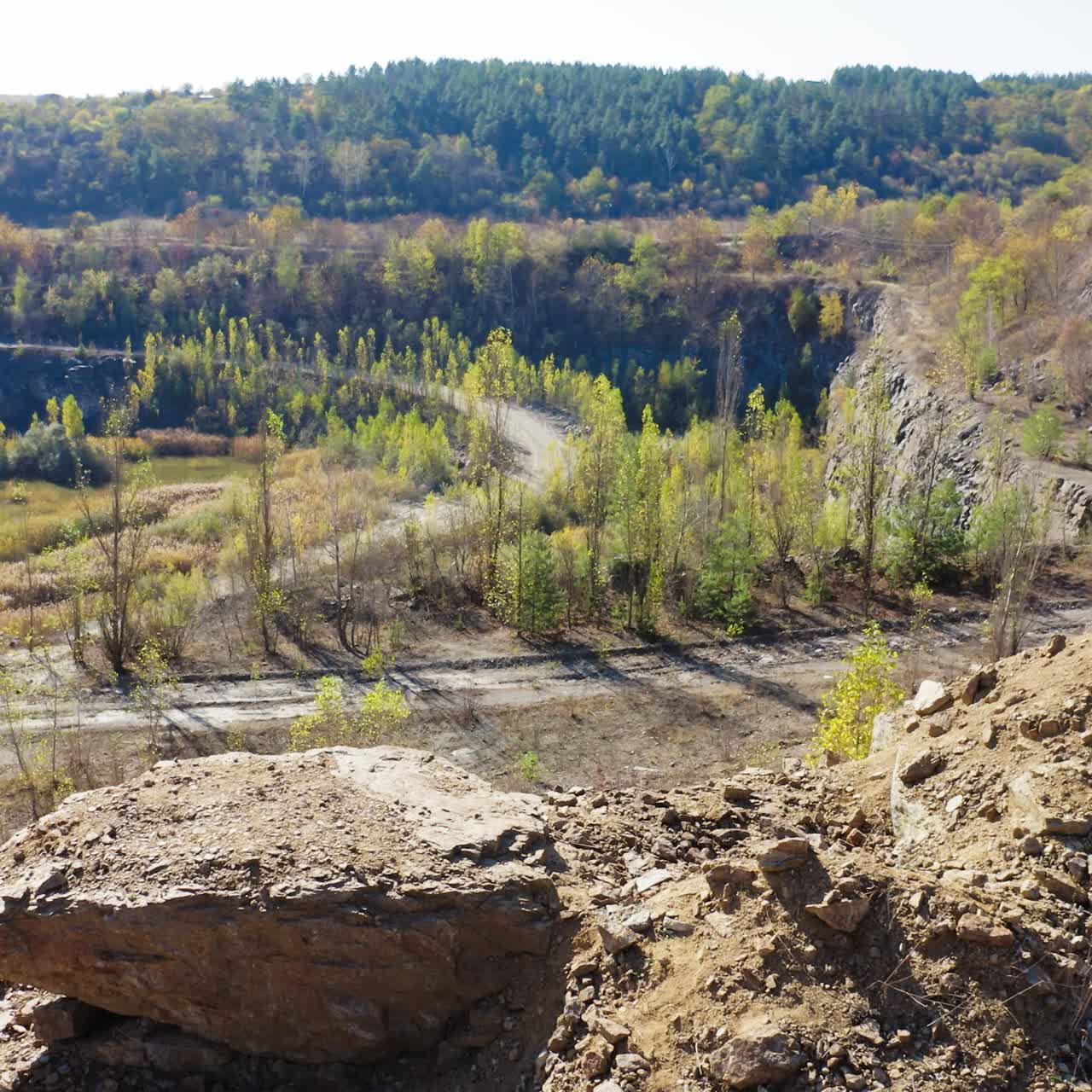 Shirtless sportsman walking in the canyon. Handsome athlete is drinking water on a beautiful nature background. Aerial view.