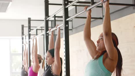 mujeres diversas sin alteración entrenando en grupo en el gimnasio haciendo abdominales en barras, en cámara lenta