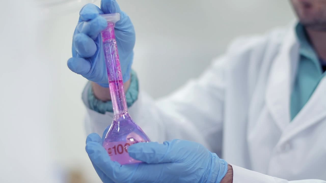 Scienziato che versa liquido rosa da provetta in matraccio