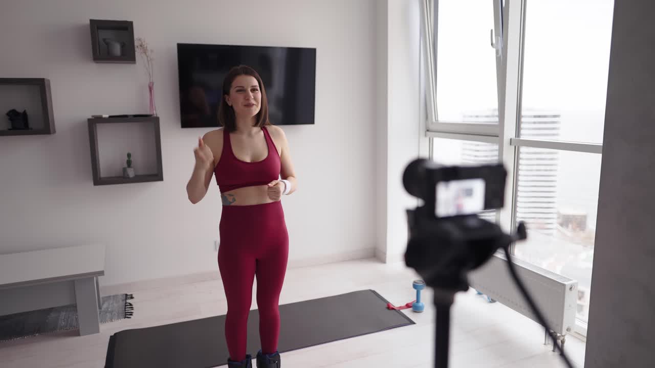 una joven instructora de fitness graba un tutorial sobre ejercicios en casa en la cámara