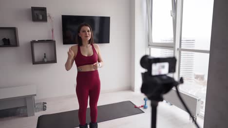 A-young-woman-fitness-instructor-records-a-tutorial-on-home-workouts-on-camera