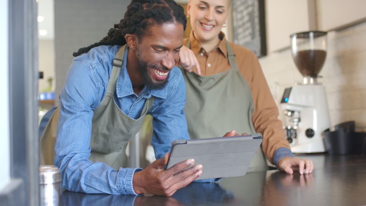 Diverse baristas tapping tablet pointing and scrolling order to prepare coffee at cafe counter
