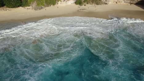 Atemberaubender-Sonnenuntergang-Am-Strand-Von-Kelingking:-4K-Drohnenvideo-Aus-Der-Luft,-Das-Gefährliche-Klippen,-Türkisfarbene-Wellen-Und-Einen-Einsamen-Strand-Auf-Bali,-Nusa-Penida,-Zeigt