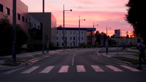 silhouette of male athlete crossing a crosswalk and running in the city at dusk