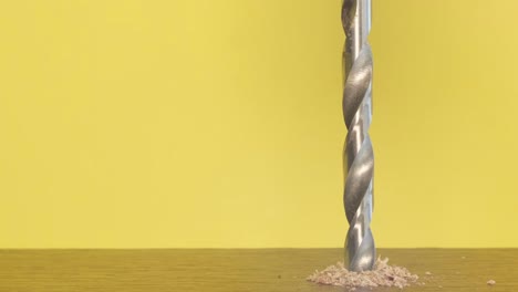 closeup of a woodworking drill rotating on a yellow background closeup of a woodworking drill rotating on a yellow background a shiny metal drill bit at work slow motion