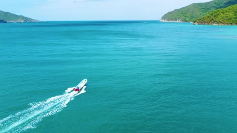 Aerial-view-following-speedboat-across-Tayrona-tropical-blue-water-to-Sierra-Nevada-de-Santa-Marta-paradise-island