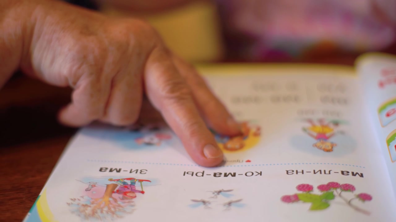 Hand of grandmother helps granddaughter to learn to read in cyrillic