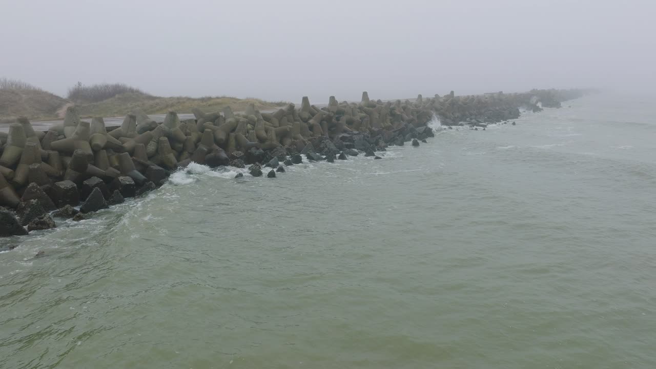 리파자 콘크리트 부두 항구, 발트해 해안선, 짙은 안개가 낀 안개 낀 날, 변덕스러운 느낌, 큰 폭풍이 튀는 것, 넓은 드론 돌리 샷이 오른쪽으로 움직이는 모습