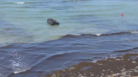Abandoned boat in the sea near algae-covered shoreline