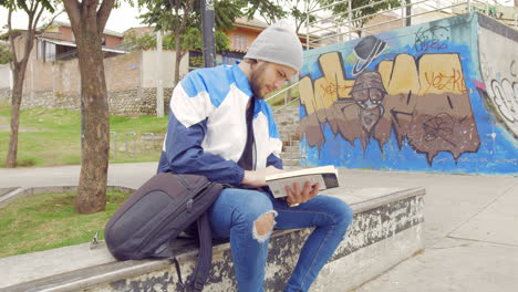 young boy reading a book on the street