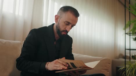 focused man in black suit reads letter alone by window in soft daylight