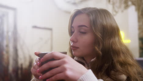 dreamy lady in brown shearling jacket sipping coffee, immersed in cozy cafe ambiance. soft lighting highlights peaceful, serene moment, capturing the tranquility of a quiet coffee break
