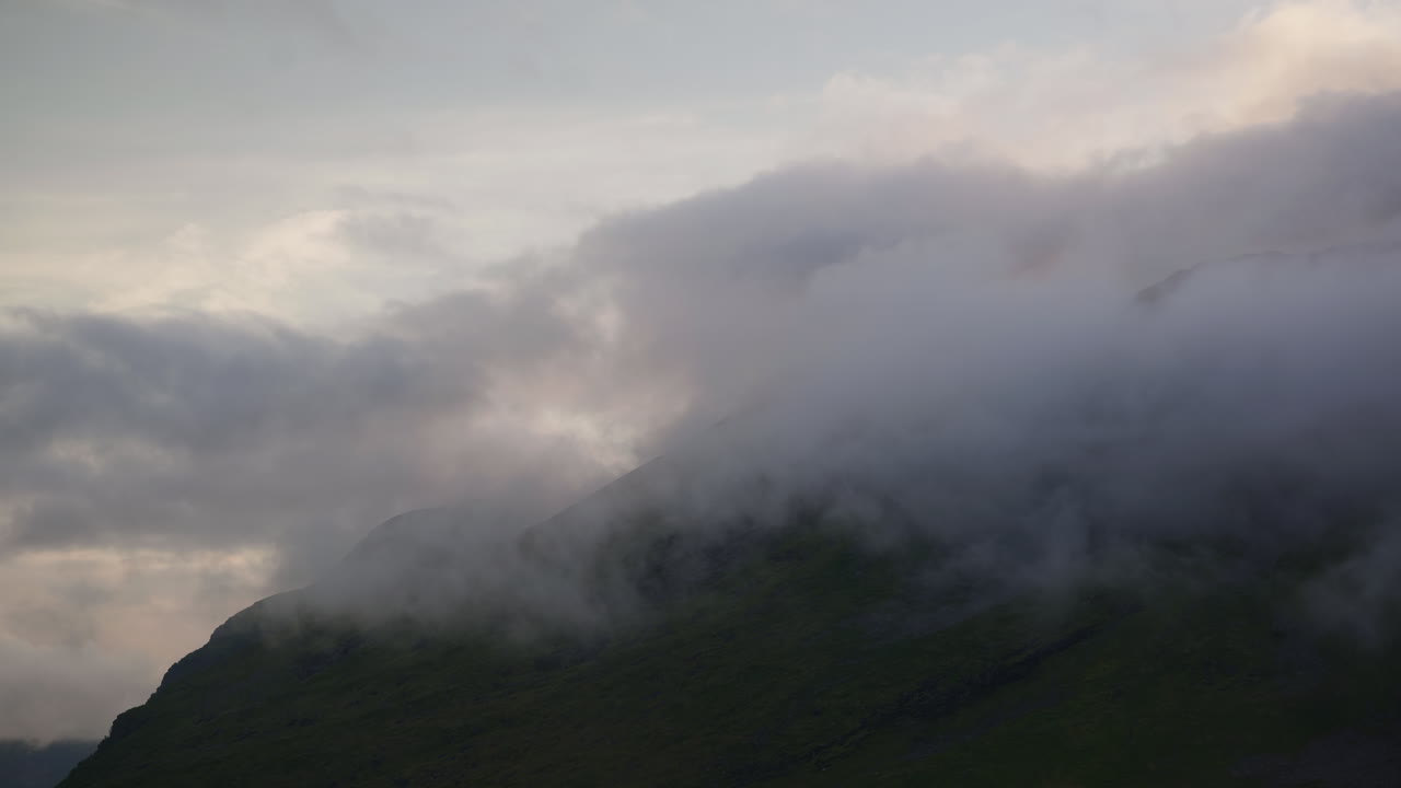 Clouds covering the mountain peaks with the sun shining over the clouds in Norway