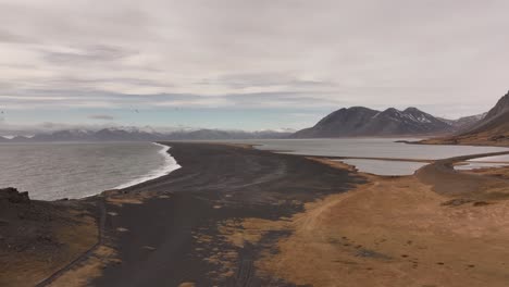 aerial view of the dramatic vestrahorn mountains and the stokksnes peninsula in iceland. black sand dunes meet the sea under a dynamic sky.