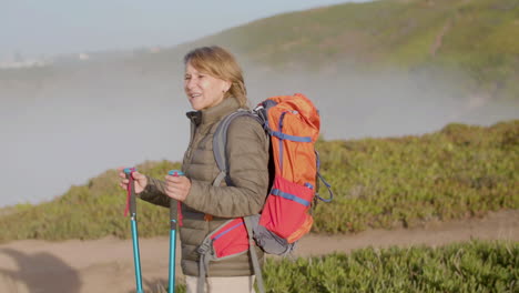 tired woman with backpack hiking on mountains with trekking poles, then having break and leaning on sticks