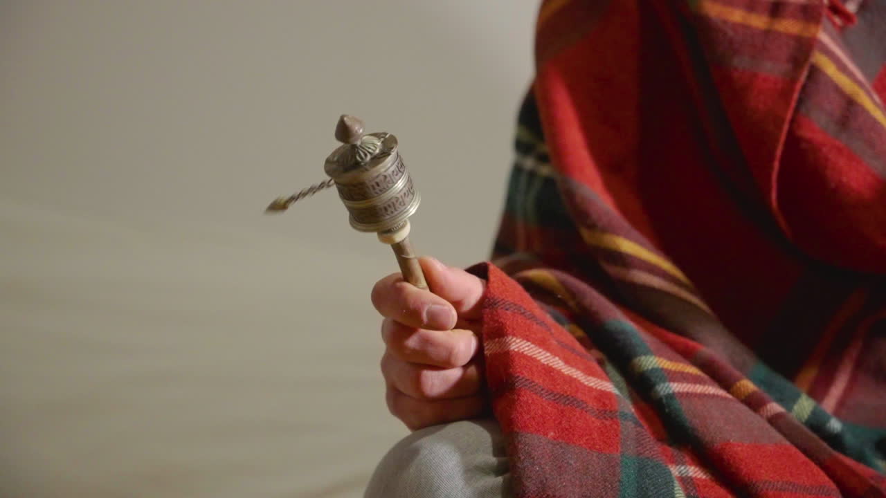 Primo piano di una mano che fa girare una ruota di preghiera tibetana