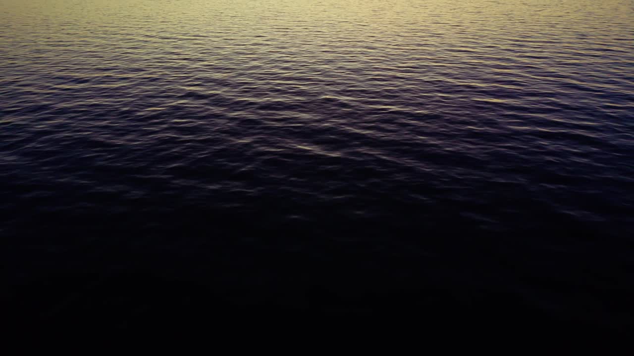 Ocean water exhibits soft ripples reflecting the warm colors of a setting sun, presenting a tranquil and serene seascape environment