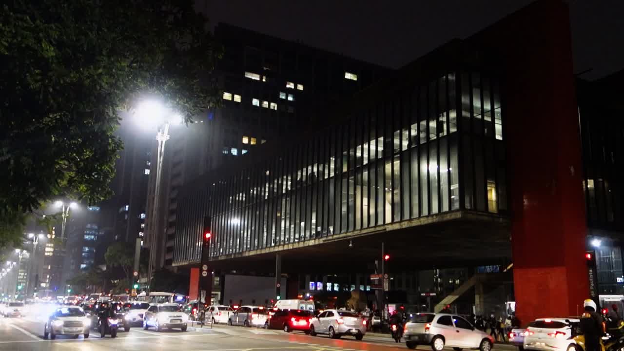 vehicular traffic on busy Paulista avenue, at night. Art museum of Sao Paulo on background