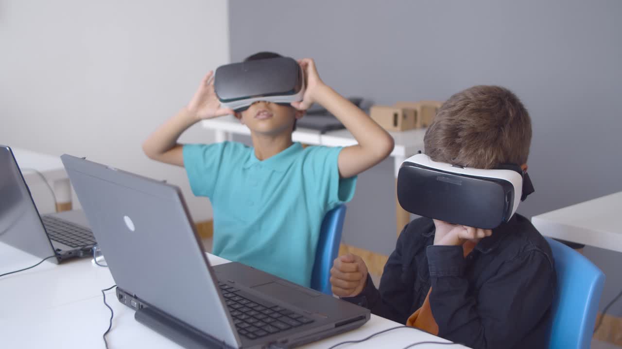 노트북과 함께 책상에 앉아 vr 헤드 ⁇ 을 착용 한 학교 소년