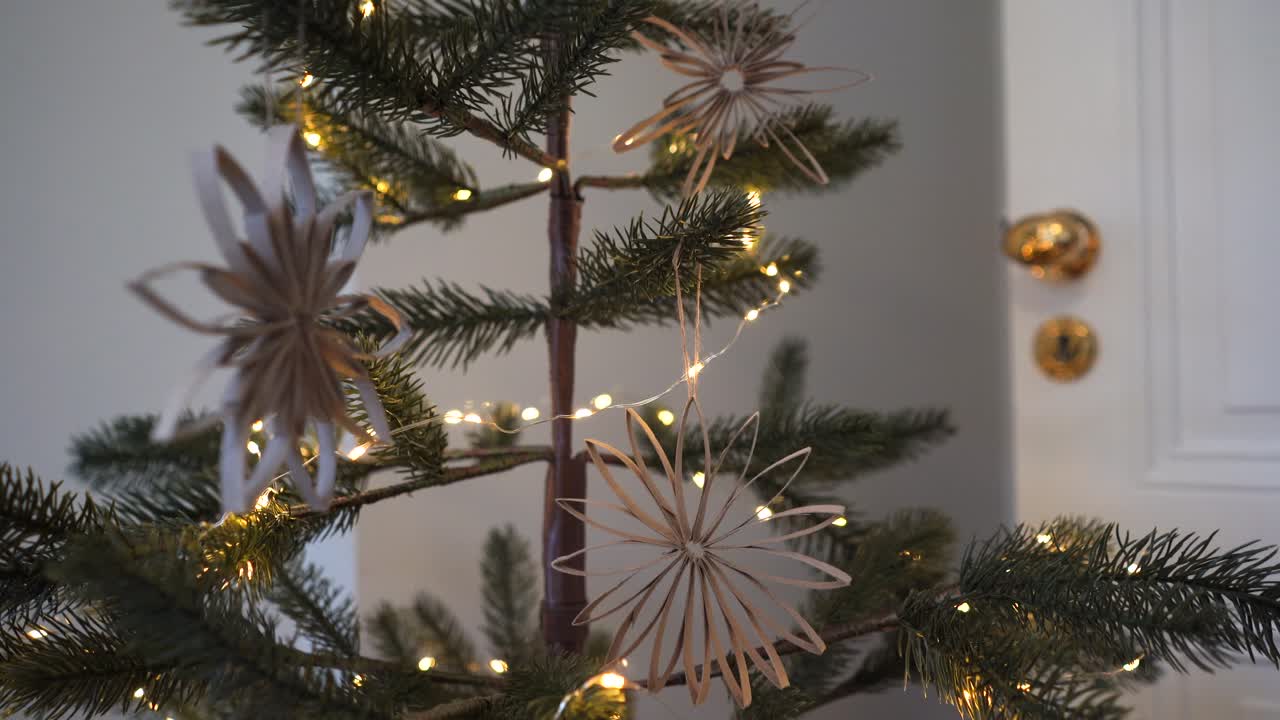 Sustainable, recyclable holiday craft ornaments on Christmas tree with lights