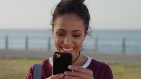 portrait cute young hispanic woman using samrtphone enjoying texting browsing online laughing reading messages on warm summer seaside