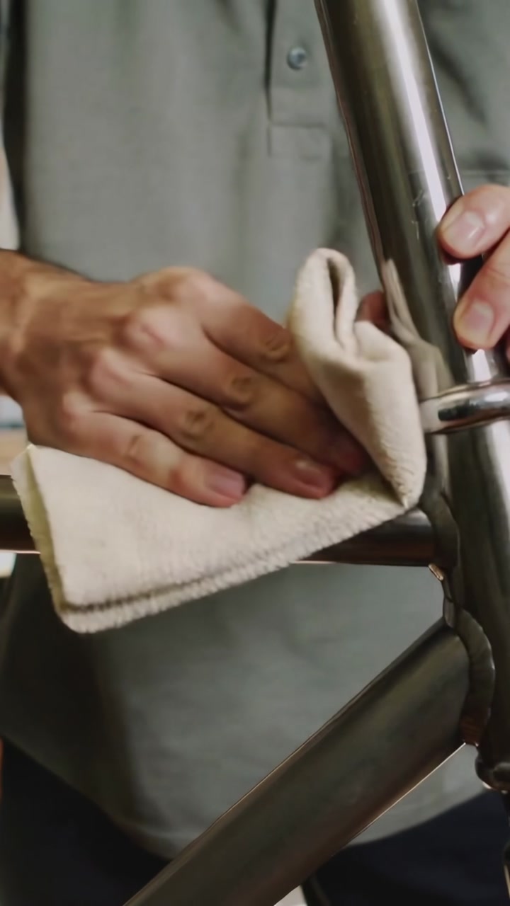 Vertical video: Pressing beige cloth, person in gray polo wiping stair rail, cleaning connector