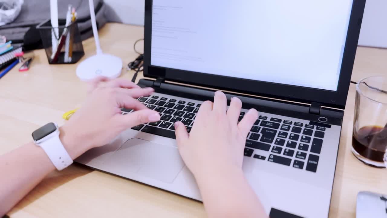 Front view of professional hands typing on a laptop keyboard.