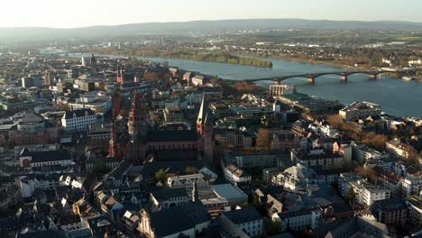 Langsame-Drohne-Schoss-Um-Mainz-Herum-Der-Rote-Dom-Mitten-In-Der-Altstadt-Mit-Dem-Rhein-Im-Rücken