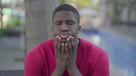 afro-american man suffering from headache in park, massaging head