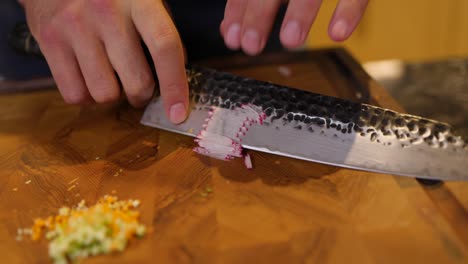 close up of chef using knife to slice radish on chopping board