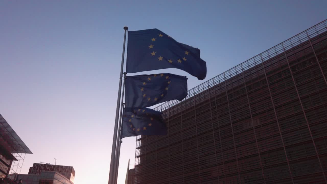 EU flags flutter in Brussels between buildings at golden hour