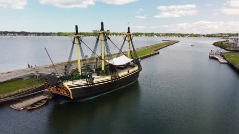 Aerial-footage-alongside-and-over-a-historical-sailing-vessel-next-to-a-jetty-in-Salem,-Massachusetts