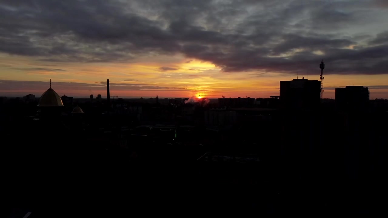Вид с воздуха на дрон, летящий над городом. Закат в небе.