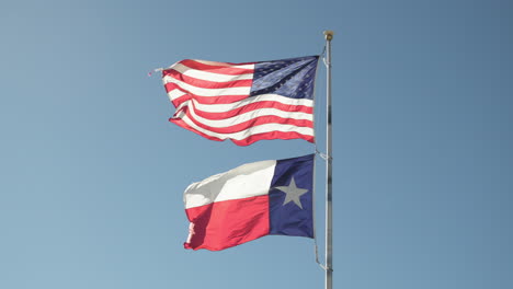 american usa starts and stripes flag with texas flag in the wind on a flag pole