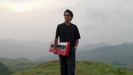 Epic-scene-of-musician-man-walking-in-slow-motion-on-hilltop-holding-a-npiano-keyboard