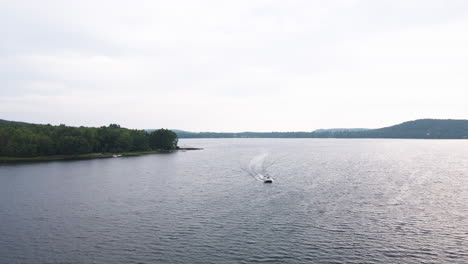 Aerial-dolly-above-speedboat-racing-across-open-lake-on-cloudy-day