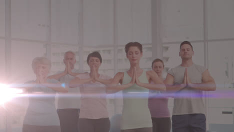 Animation-of-glowing-light-over-people-practicing-yoga