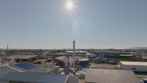 flying towards a chimney in an industrial area on a clear, sunny day. otaki, new zealand.