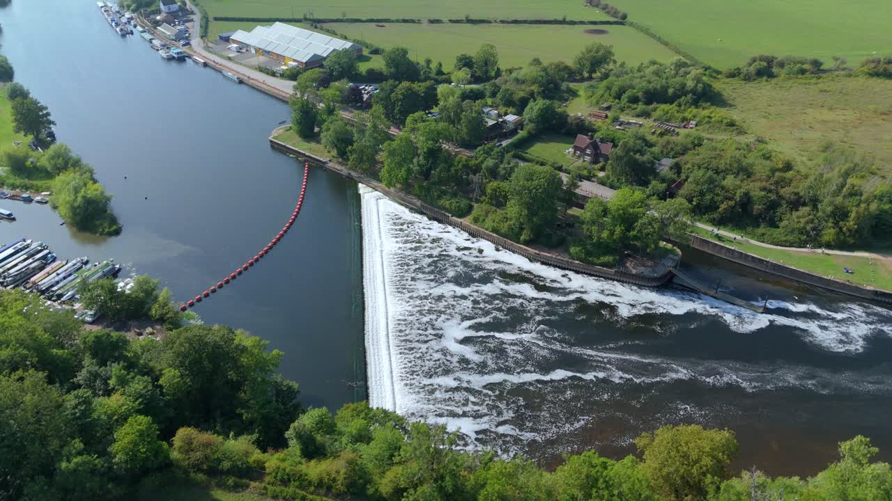 Drone aerial view of Gunthorpe Weir on River Trent Nottinghamshire with navigation canal, green countryside fields and summer sunset evening sky