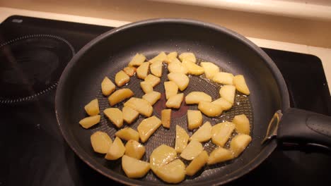 pieces of cut potatoes frying in a pan with cooking oil