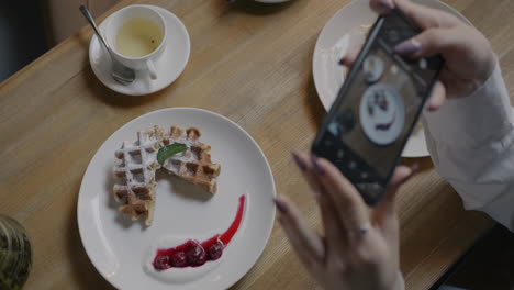 Taking a photo of a delicious waffle with tea at a cafe.