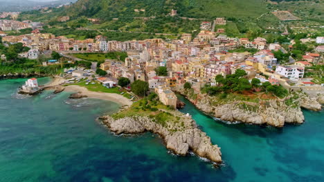 aerial forwarding shot of amazing landscape of sicily along the beautiful coastal town of caletta sant'elia, santa flavia pa, italy on a cloudy day