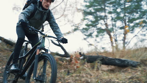 athlete cyclist man with backpack and helmet riding a mountain bike down the hill in the countryside