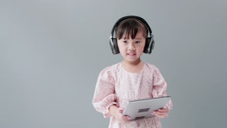 Chica-Con-Vestido-Bailando-Y-Girando-Con-Auriculares-Frente-A-Un-Fondo-Gris