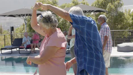 happy diverse senior friends dancing by pool at sunny garden party, unaltered, in slow motion